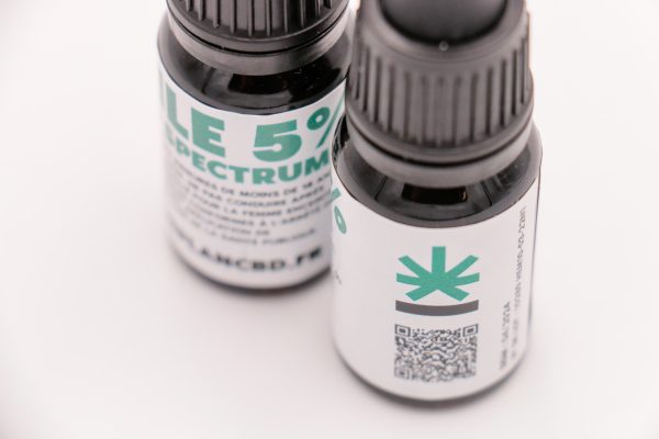 Gros plan sur les étiquettes arrière de deux flacons d'huile CBD MONPLANCBD montrant un logo et un QR code - CBD testé laboratoire.