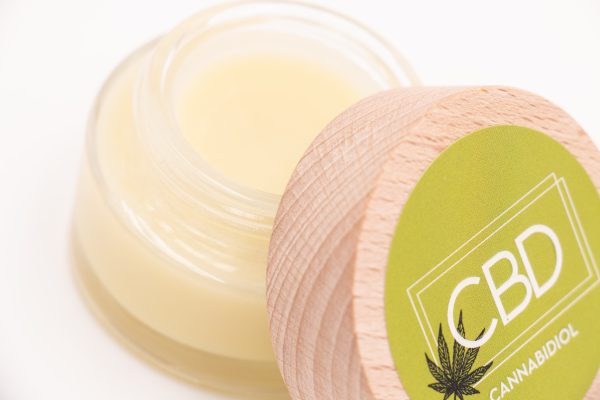 Pot de Baume Relaxant CBD Bio MONPLANCBD ouvert, montrant la texture onctueuse jaune pâle du baume.