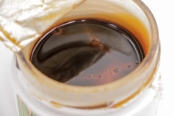Pot de Rosin CBD MONPLANCBD (61.83%) avec sceau de fraîcheur partiellement ouvert, révélant le concentré liquide ambré - CBD Qualité Premium.