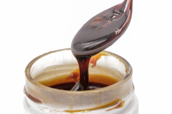 Gros plan sur le Rosin CBD liquide MONPLANCBD (61.83%) coulant d'un outil de dab dans un pot - Meilleur haschisch CBD.