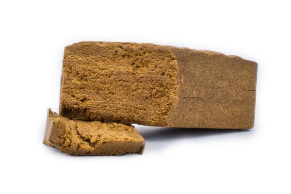 Bloc de hash CBD A6 Dry Sift 120u sur fond blanc, montrant sa texture sableuse.
