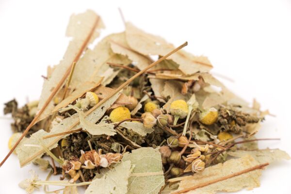 Gros plan sur le mélange de l'infusion CBD sommeil, montrant les fleurs de camomille jaune, les feuilles de tilleul et les fleurs de chanvre.