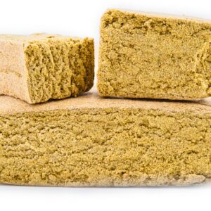 Pyramide de trois blocs de haschisch CBD Apple Pie, montrant sa texture friable et sa couleur dorée sur fond blanc.