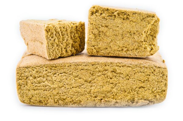 Pyramide de trois blocs de haschisch CBD Apple Pie, montrant sa texture friable et sa couleur dorée sur fond blanc.